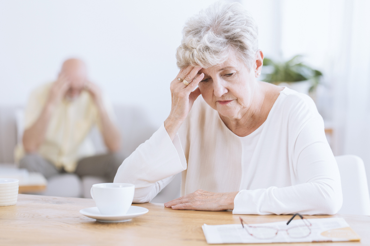 an elderly woman touching her head