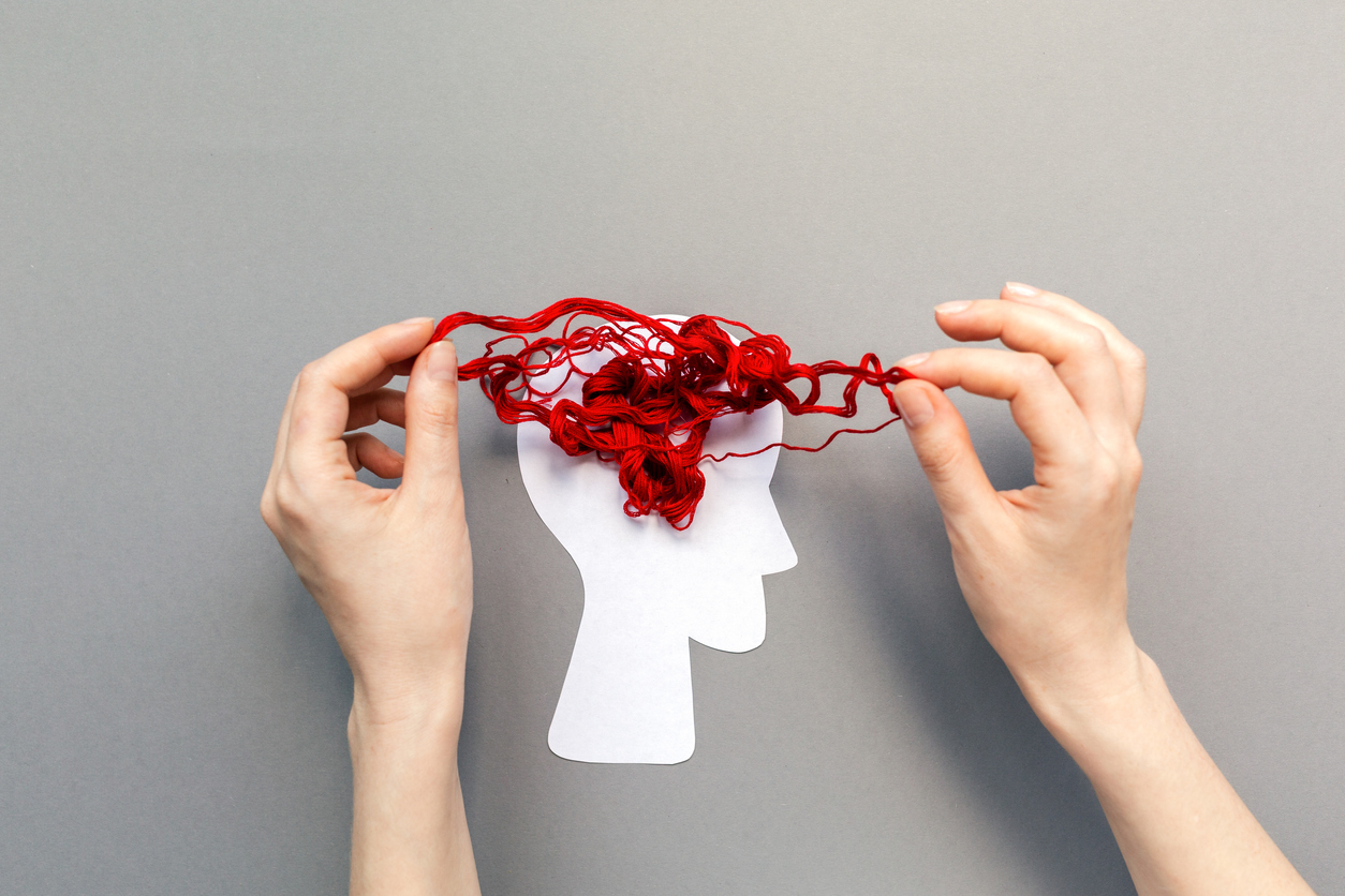 female's hands unravel the tangled red threads on the silhouette of the head, representing the brain