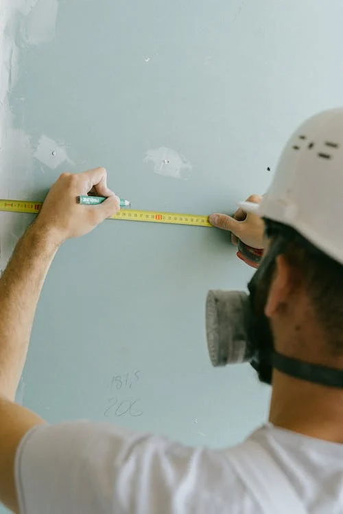 A construction worker holding a pencil and measuring tape