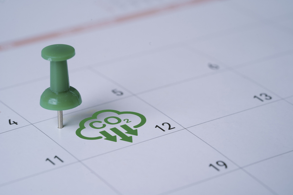 Carbon credit and zero emission concept with green push pin marking CO2 reduction deadline on calendar representing net zero target to prevent climate change and business sustainability management