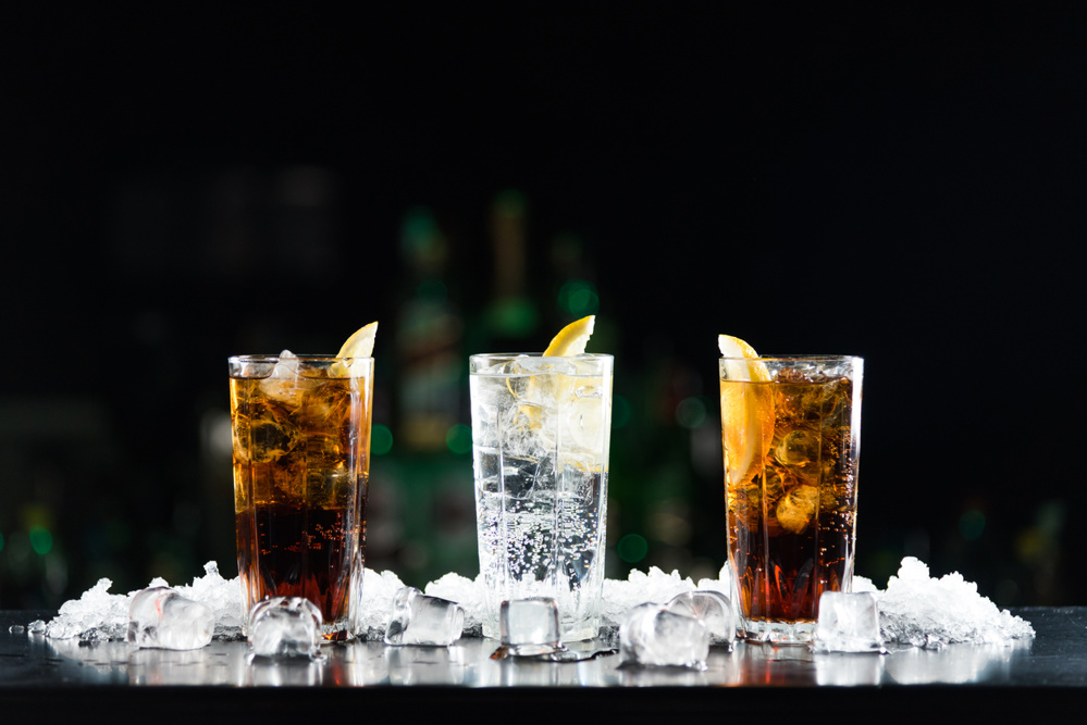Two whisky and coke cocktails and one white alcoholic drink on the bar table. Photo